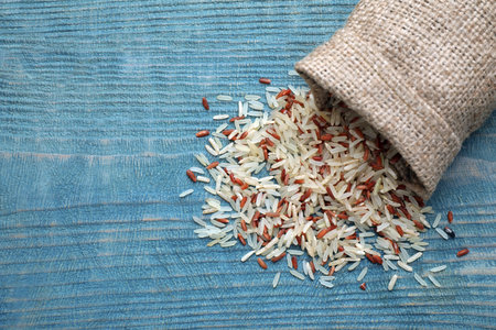 Mix of brown and polished rice in bag on blue wooden table, top viewの写真素材