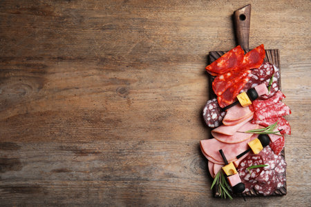 Tasty ham with other delicacies served on wooden table, top view. Space for textの写真素材
