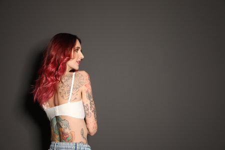 Beautiful woman with tattoos on body against black background. Space for textの写真素材