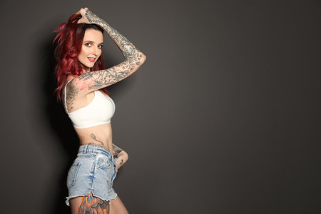 Beautiful woman with tattoos on body against black background. Space for textの写真素材