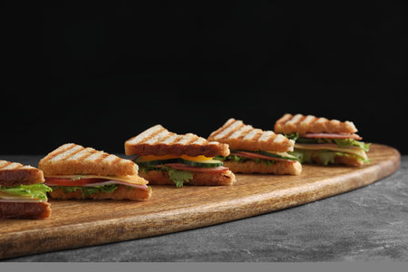 Tasty sandwiches with ham on gray table