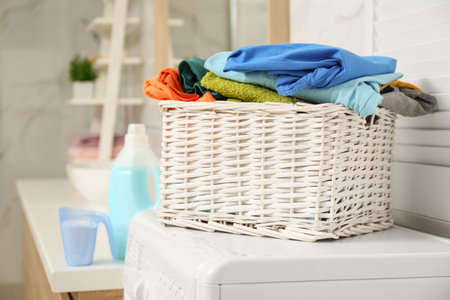 Wicker basket with laundry on washing machine in bathroomの写真素材