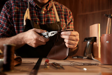 Man sewing piece of leather at table, closeup