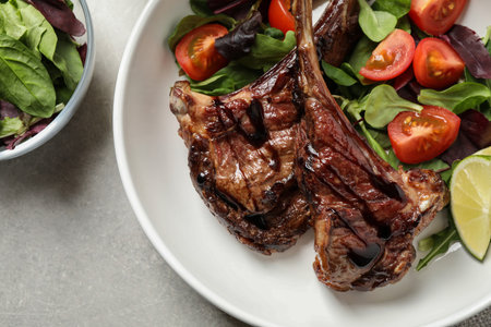 Delicious grilled ribs served on light gray table, flat lay