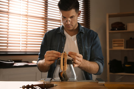 Man sewing piece of leather workshop