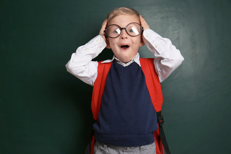 Funny little child wearing glasses near chalkboard. First time at schoolの写真素材