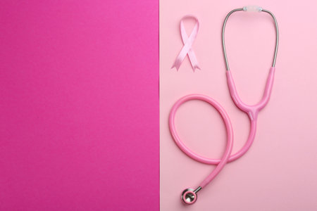 Pink ribbon as breast cancer awareness symbol and stethoscope on color background, flat lay. Space for textの写真素材