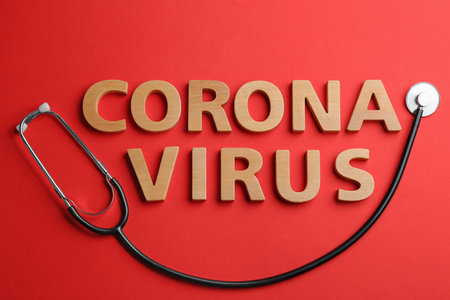 Words CORONA VIRUS made of wooden letters and stethoscope on red background, flat layの写真素材