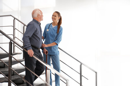 Doctor helping senior patient in modern hospitalの写真素材