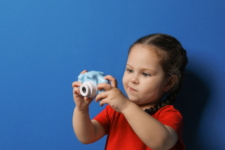 Little photographer taking picture with toy camera on blue backgroundの写真素材