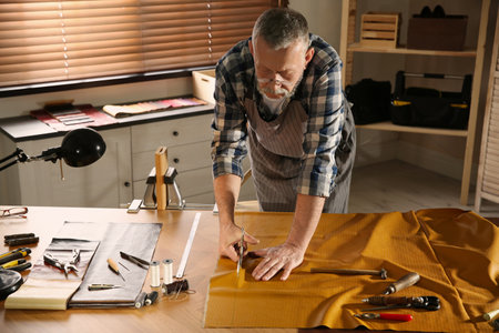 Man cutting leather with scissors in workshop