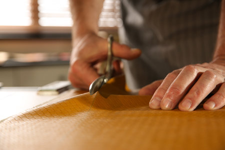 Man cutting leather with scissors in workshop, closeupの写真素材