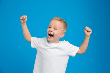 Portrait of cute little boy on light blue backgroundの写真素材