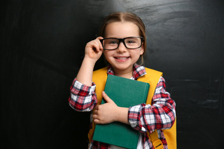 Cute little child wearing glasses near chalkboard. First time at schoolの写真素材