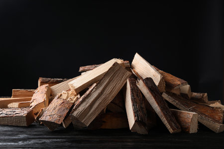 Cut firewood on table against black background