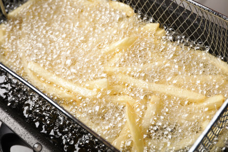 Cooking delicious french fries in hot oil, closeupの写真素材