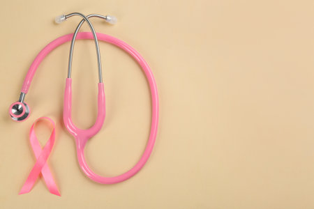 Pink ribbon and stethoscope on beige background, flat lay with space for text. breast cancer conceptの写真素材