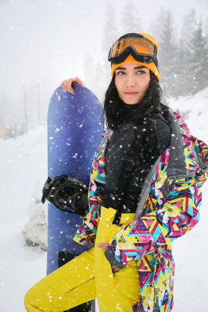 Young woman with snowboard wearing winter sport clothes outdoors
