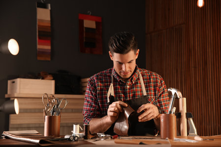 Man sewing piece of leather workshop