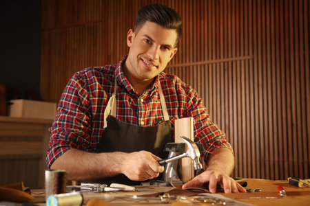Man working with piece of leather at table in atelierの写真素材
