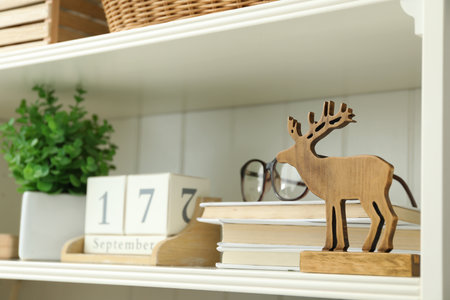 White shelving unit with wooden deer figure, books and calendarの写真素材