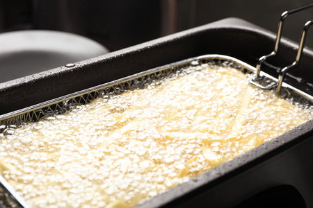 Cooking delicious french fries in hot oil, closeup