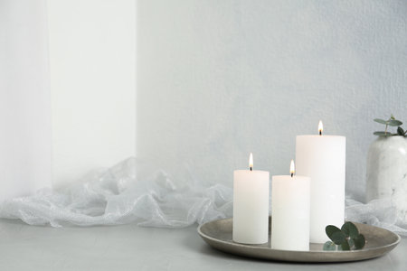 Burning candles on light gray stone table. Space for textの写真素材