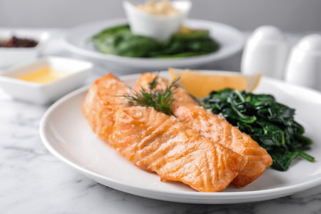 Tasty salmon with spinach and lemon on tableの写真素材