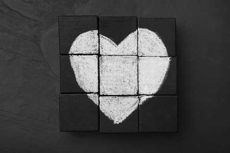 Heart drawn on black cubes, flat lay. Composition symbolizing problems in relationshipの写真素材