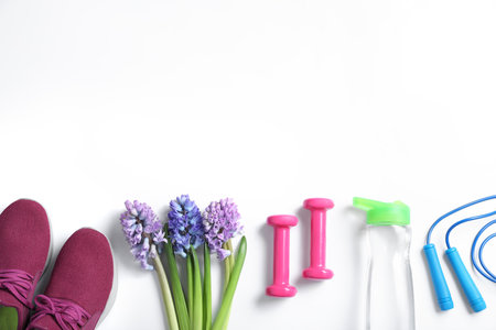 Composition with spring flowers and sports items on white background, flat lay. Space for textの写真素材