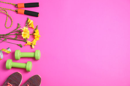 Flat lay composition with spring flowers and sports items on pink background. Space for textの写真素材