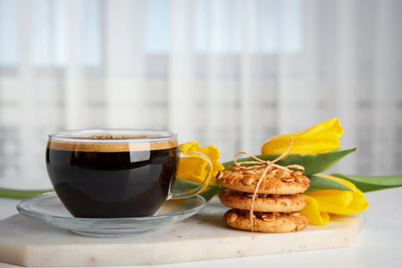 Aromatic morning coffee, cookies and beautiful flowers on white tableの写真素材