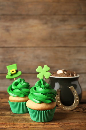 Decorated cupcakes and pot with gold coins on wooden table. St. Patrick's Day celebrationの写真素材