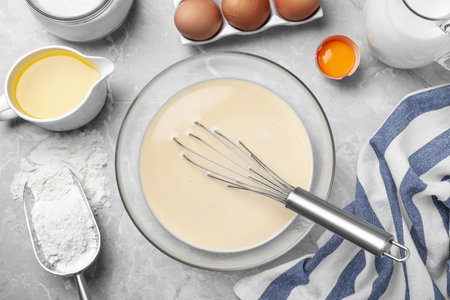 Batter for thin pancakes and products on light gray table, flat lay