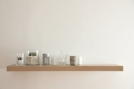 Wooden shelf with plants and decorative elements on light wallの写真素材