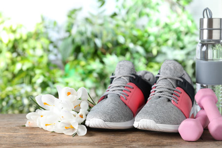 Composition with spring flowers and sports items on wooden table against blurred greeneryの写真素材