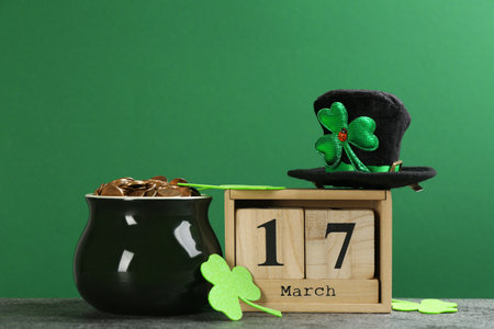 Composition pot of gold coins and wooden block calendar on gray stone table against green...