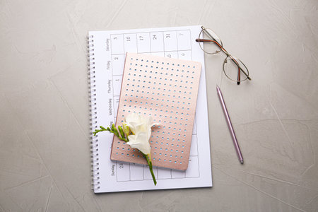 Flat lay composition with calendar, notebook and beautiful flower on gray table