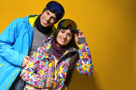 Couple wearing stylish winter sport clothes on yellow backgroundの写真素材