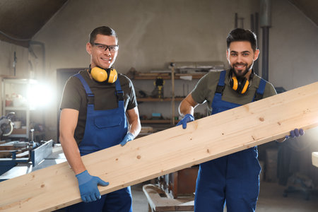 Professional carpenters with large wooden board in workshopの写真素材