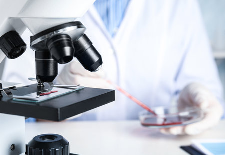 Slide with blood sample on microscope in laboratory, closeup. virus research