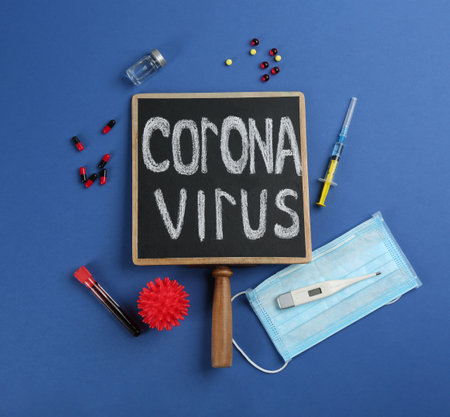 Chalkboard with words CORONA VIRUS, test tube and syringe on blue background, flat layの写真素材