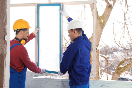 Workers in uniform dismantling old window indoorsの写真素材