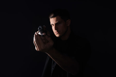 Professional killer with gun on black background