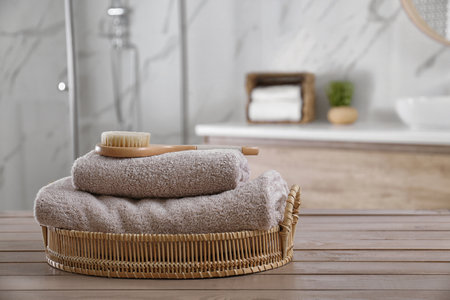 Clean towels and shower brush on wooden table in bathroomの写真素材
