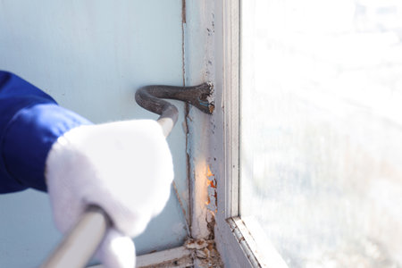 Worker dismantling old window with crowbar indoors, closeupの写真素材