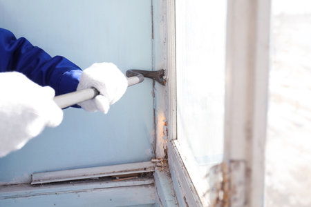 Worker dismantling old window with crowbar indoors, closeupの写真素材