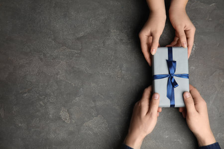 Daughter giving present to her dad over gray stone table, top view with space for text. Happy father's dayの写真素材