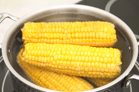 Pot with boiling fresh corn on cooktop, closeupの写真素材