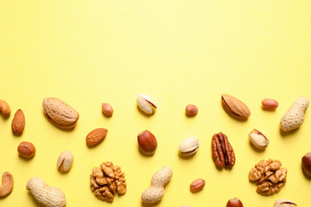 Different delicious nuts on yellow background, flat lay. Space for textの写真素材